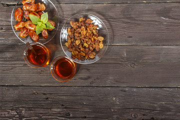 Traditional Arabic, Turkish Ramadan tea with dry dates and raisins on a wooden black table. Ramadan. Turkish fresh tea with dates. View from above.
