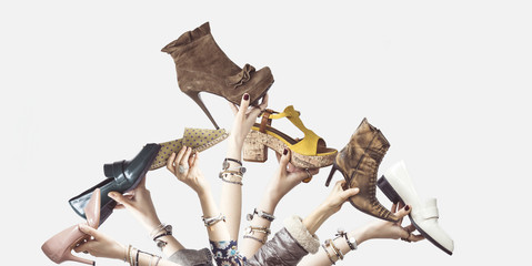 Hands holding different shoes on isolated background