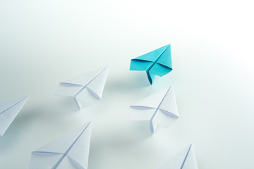 Business leadership concept with blue paper plane leading among white.