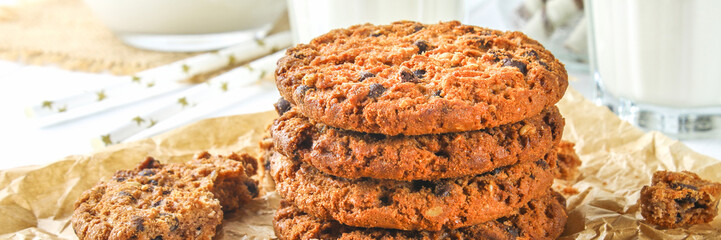 Homemade oatmeal cookies. A parchment paper on the background. Milk on a wooden white table.