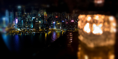 Blured burning candle in glass cup with Hong Kong island night view background