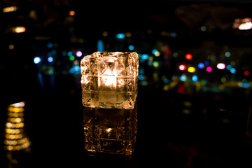 Burning candle in glass cup with abstract background