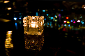 Burning candle in glass cup with abstract background
