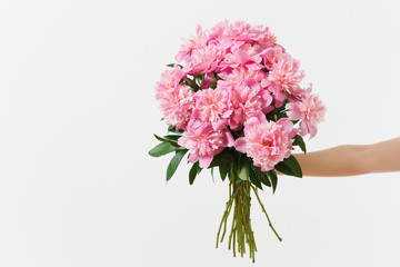 Female hand holding beautiful bouquet of pink peonies flowers isolated on white background. St. Valentine's Day, International Women's Day holiday concept. Advertising area, copy space advertisement