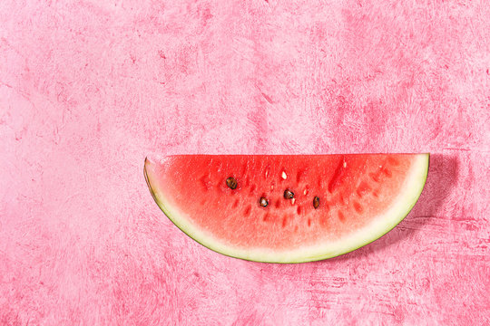 Ripe slice of watermelon over pink texture background. Flat lay, space.