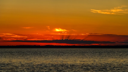 Red sky in the sunset behind clouds and woods by the sea. Sweden