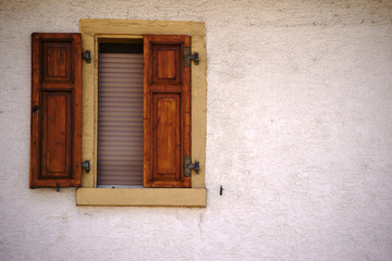 Fototapeta na wymiar Fenster mit Fensterladen / Ein Wohnhaus mit einem geschlossenen Fenster mit Fensterladen.