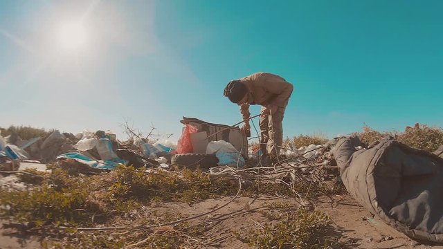 dirty homeless man at the dump slow motion lifestyle video. homeless roofless person looking for food in a dump. refugee homeless illegal immigration poverty concept
