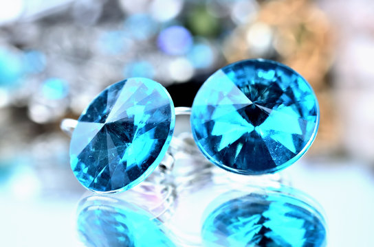 Close-up of blue earrings jewels - reflection effect - colored backgrounds