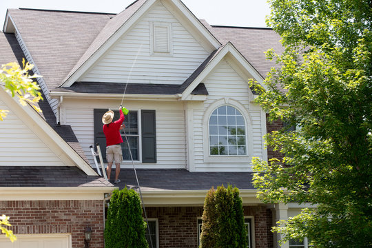 Man cleaning the upper floor exterior of his home