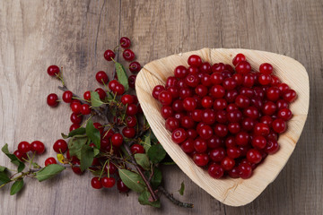 fresh red cherries in a wooden plate on a wooden table. wooden plate on a wooden background.