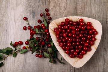 fresh red cherries in a wooden plate on a wooden table. wooden plate on a wooden background.