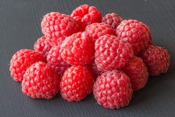 Fresh and tasty looking raspberries on a black wooden table