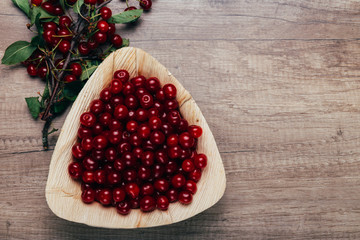 fresh red cherries in a wooden plate on a wooden table. wooden plate on a wooden background.