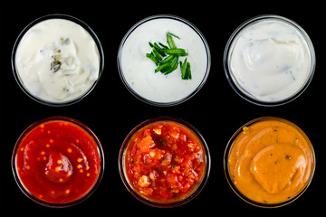 Set of different delicious sauces for dishes isolated on black b