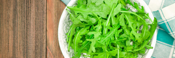 Fresh juicy leaves of arugula on a brown wooden table. banner