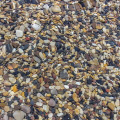 sea stones under blue water. Background of small multicolored stones lying under water.