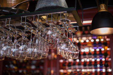 Clean washed glasses hanging over a bar rack