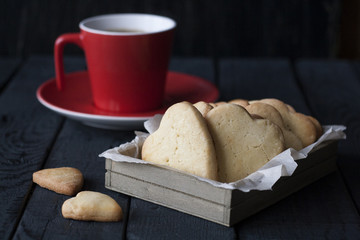 Tasty homemade gingerbread and coffee in a red cup on a black wooden background.