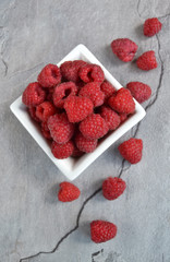 Fresh red raspberries in white square plate. Raspberry background.