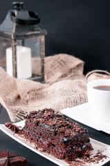 Chocolate cake and black tea, coffee on a black wooden background