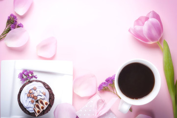 Chocolate cupcake with icing, coffee in a white cup on a pink gentle background