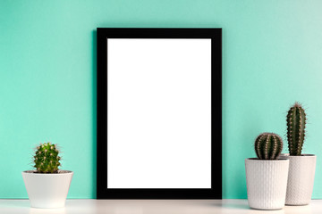 Empty black frame with cactuses on the background of the mint wall
