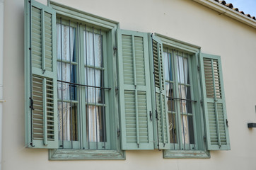 Old light green wooden windows with shutters in Mediterranean style. Vintage background. Cyprus, Nicosia.