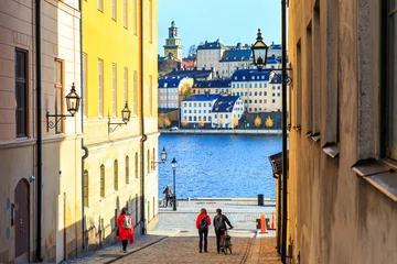 Fotobehang Toeristen die op geplaveide straten lopen in Riddarholmen maakt deel uit van Gamla Stan is de oude binnenstad van Stockholm, Zweden. Gevels van middeleeuwse huizen en buitenkant van historische gebouwen aan de oever van de Oostzee. © goncharovaia