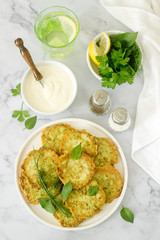 Pancakes from zucchini, served with sour cream or yogurt and various herbs. Useful vegetarian food.