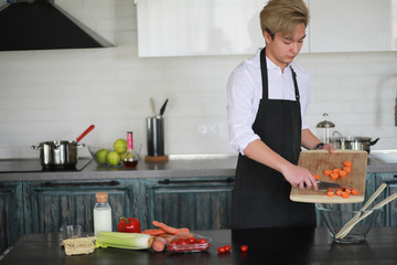 Asian cook in the kitchen prepares food in a cook suit