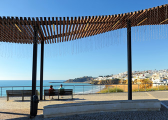 Dos turistas de edad avanzada sentados en un banco en la playa de Albufeira, uno de los más visitados por el turismo europeo. Algarve, al sur de Portugal.