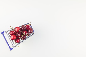 Ripe cherries in a shopping cart isolated