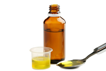 Bottle, measuring plastic cup and spoon with medical syrup on white background