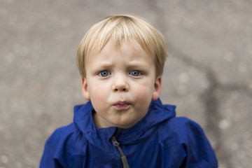 Outdoor portrait of beautiful toddler boy looking at camera