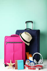 Blue and pink suitcases with clothes, headphones, passport and diving mask on wooden table