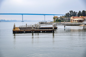 Paddle Boarder Glides under a Fishing Pier