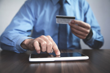 Man holding credit card and using tablet.