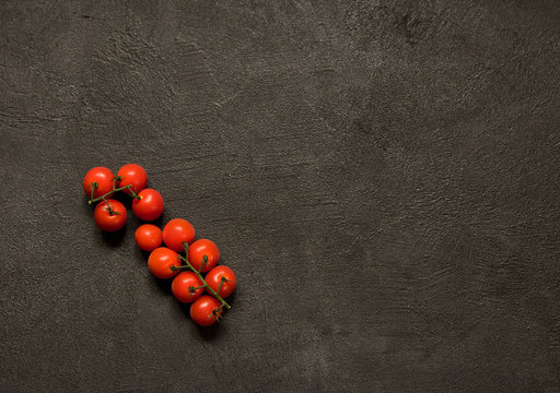 Red tomatoes on black stone surface copy space. Natural healthy vegetarian food.