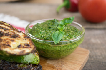 Grilled spicy zucchini with pepper and pesto sauce on a gray concrete background. Selective background.
