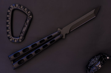 Knife balisong. A black watch and a military carbine.
