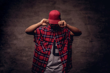 Portrait of an African-American dancer guy dressed in a red fleece shirt and cap at the studio....