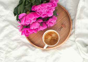 Peonies and coffee on the bed, top view