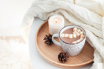 Hot cocoa with marshmallows, knitted sweater and burning candle