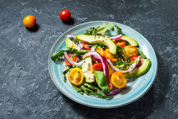 Salad with tomatoes and avocado on stone background
