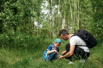 A man with a backpack, a father and his son on a hike, walking during walks in the woods. Family life, pastime with the family, the upbringing of children.