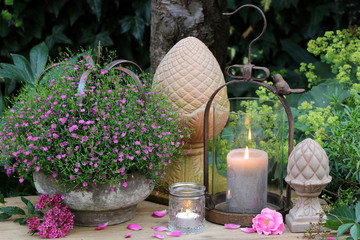 Gartendekoration mit Kerzen und Sommerblumen in Pink