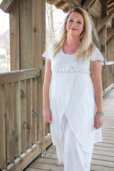 Mollige blonde Frau in weißem Kleid unter Holzbrücke