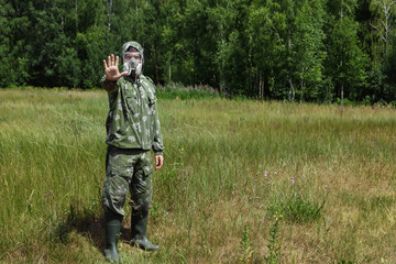 A man in a respirator and glasses and a camouflage suit against the background of nature. Chemical armies.