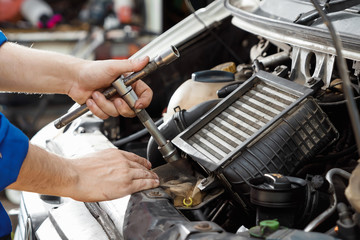 Male hands close-up with wrenches. The auto mechanic works in the garage. Repair service. Maintenance of the car, car repair.